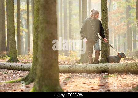 Forester o hunter nella foresta con un cane come un cane da caccia in una passeggiata Foto Stock