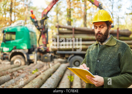 Silvicoltura o lavoratore di foresta con lista di controllo quando il caricamento dei registri lungo Foto Stock