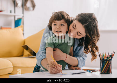 Madre e figlio di Disegno con matite di colore in salotto Foto Stock