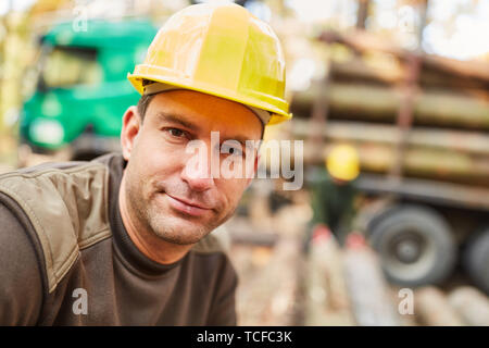 Ritratto di giovane forestali o lavoratore della foresta durante il caricamento di legno lunga Foto Stock