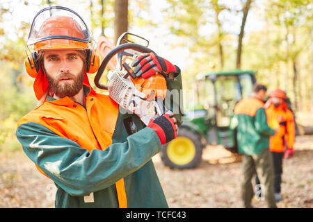 Lavoratore della foresta o foresta agricoltore come un taglialegna con chainsaw e gli indumenti di protezione Foto Stock