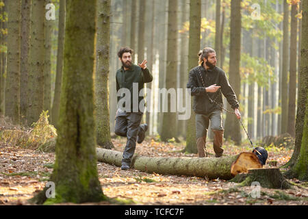 Due cacciatori con un falco come un cane di sudore o il tracking cane nel distretto di foresta Foto Stock