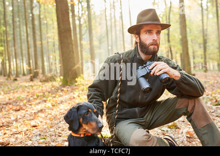 Hunter o forester con hawk come hound caccia la caccia nel bosco Foto Stock