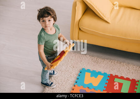 Vista aerea del bambino carino in verde t-shirt giocando con tappetino puzzle Foto Stock