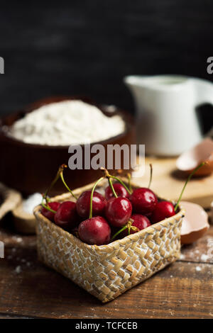 Primo piano degli ingredienti per preparare una coca de cireres, una ciliegia dolce torta piatto tipico della Catalogna, Spagna, come ad esempio farina di grano, latte, zucchero, uova Foto Stock