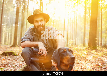 Sorridente hunter o ranger nella foresta con bracke come un cane da caccia Foto Stock