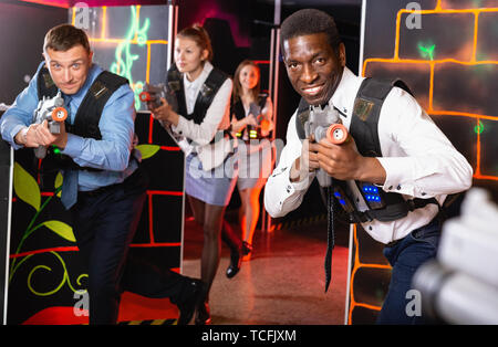 Gruppo di sorridenti colleghi azienda pistole laser giocando tag laser game Foto Stock