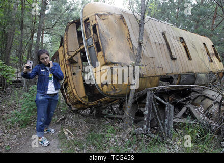 Kiev, Ucraina. Il 7 giugno, 2019. Un visitatore assume un selfie davanti un bus abbandonate durante un tour nella città fantasma di pripjat di Chernobyl in Ucraina, il 7 giugno 2019. Il successo di un'U.S. Del HBO miniserie televisiva "Chernobyl' ha rinnovato interesse in tutto il mondo su dell'Ucraina 1986 catastrofe nucleare. Turismo a Cernobyl ha spiked 40% dopo il debutto della serie HBO in maggio, agenzie di giro riportato . Credito: ZUMA Press, Inc./Alamy Live News Foto Stock