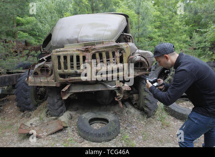 Kiev, Ucraina. Il 7 giugno, 2019. Una donna prende la foto di un relitto del carrello nella città fantasma di pripjat di Chernobyl, in Ucraina, il 7 giugno 2019. Il successo di un'U.S. Del HBO miniserie televisiva "Chernobyl' ha rinnovato interesse in tutto il mondo su dell'Ucraina 1986 catastrofe nucleare. Turismo a Cernobyl ha spiked 40% dopo il debutto della serie HBO in maggio, agenzie di giro riportato . Credito: ZUMA Press, Inc./Alamy Live News Foto Stock