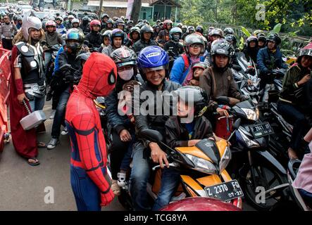 West Java, Indonesia. 8 Giugno, 2019. Un funzionario di polizia in costume di Spiderman cerca di intrattenere un bambino con i suoi genitori in moto in un ingorgo su persone di viaggio di andata e ritorno dal proprio villaggio dopo l'Eid al-Fitr in Nagrek di Bandung, regione occidentale di Giava, Indonesia, Giugno 8, 2019. Credito: Septianjar/Xinhua/Alamy Live News Foto Stock