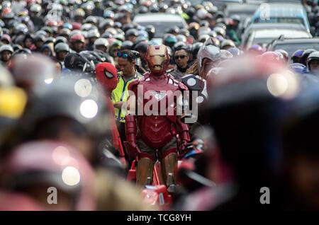 West Java, Indonesia. 8 Giugno, 2019. Un funzionario di polizia in costume Ironman sorge in un ingorgo su persone di viaggio di andata e ritorno dal proprio villaggio dopo l'Eid al-Fitr in Nagrek di Bandung, regione occidentale di Giava, Indonesia, Giugno 8, 2019. Credito: Septianjar/Xinhua/Alamy Live News Foto Stock