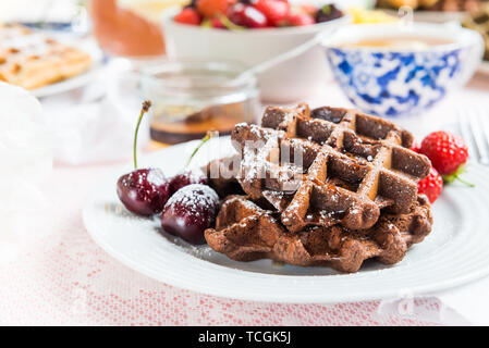 Tavolo per la prima colazione con cioccolato Banana Waffle. Il miele, fragole e ciliege nelle vicinanze Foto Stock