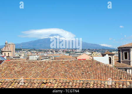 Incredibile paesaggio di siciliano di Catania, Italia con tetti di edifici storici nella città vecchia e il maestoso vulcano Etna in background. La neve sulla cima della montagna. Giornata di sole. Foto Stock