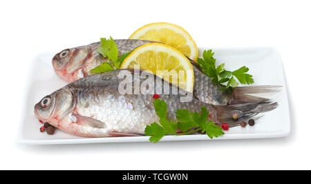 Pesce fresco con limone e prezzemolo sulla piastra isolata su bianco