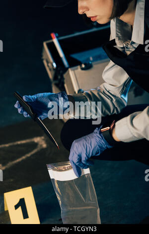 Vista ritagliata di investigatore tenendo il coltello e sacchetto ziploc alla scena del crimine Foto Stock
