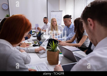 Il gruppo di società multietnica Diverse Busy business persone sedute insieme al tavolo in ufficio Foto Stock