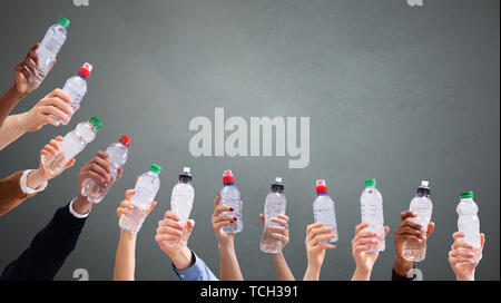 Gruppo di diverse persone che trattengono le bottiglie di acqua in una fila contro lo sfondo di colore verde Foto Stock