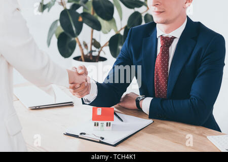 Ritagliato colpo di imprenditore nel soddisfare stringono le mani con il client vicino casa modello Foto Stock