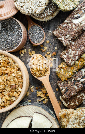 Spuntini salutari. Integratori alimentari. Halva di sesamo. Fiocchi, chia semi in due ciotole e cucchiai. Kozinaki, tre barrette energetiche e le foglie di menta. I grissini con fla Foto Stock