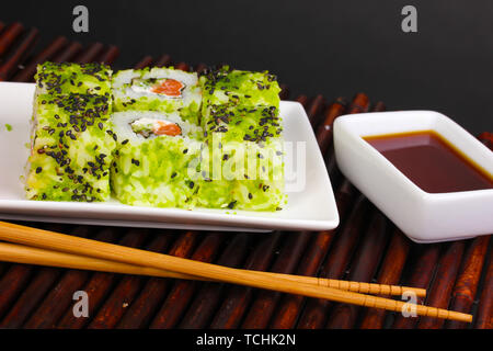 Gustosi panini serviti sulla piastra bianca con bacchette sul tappetino di bambù su sfondo nero Foto Stock