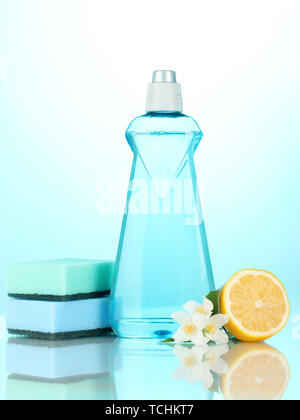 Detersivo liquido per stoviglie con spugne e limone con fiori su sfondo blu Foto Stock