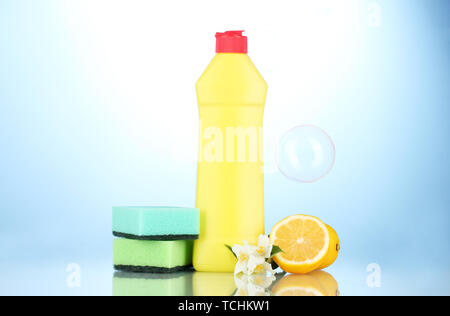 Detersivo liquido per stoviglie con spugne e limone con fiori su sfondo blu Foto Stock