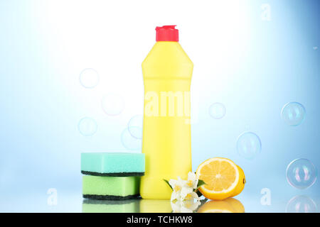 Detersivo liquido per stoviglie con spugne e limone con fiori su sfondo blu Foto Stock