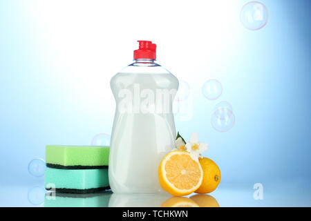 Detersivo liquido per stoviglie con spugne e limone con fiori su sfondo blu Foto Stock
