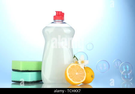 Detersivo liquido per stoviglie con spugne e limone con fiori su sfondo blu Foto Stock