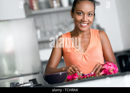 Sorridente giovane massaia rendendo frutta insalata fresca