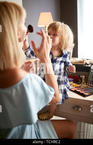 Cute girl abbellisce la sua madre con il make up Foto Stock