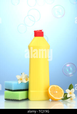 Detersivo liquido per stoviglie con spugne e limone con fiori su sfondo blu Foto Stock