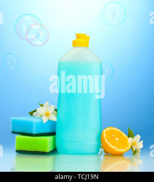 Detersivo liquido per stoviglie con spugne e limone con fiori su sfondo blu Foto Stock