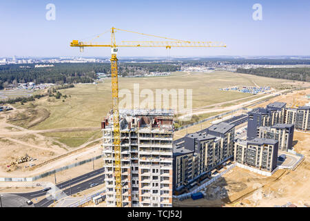 Drone immagine della città sito in costruzione con giallo Industrial Gru a torre alto permanente sul cielo blu sullo sfondo Foto Stock