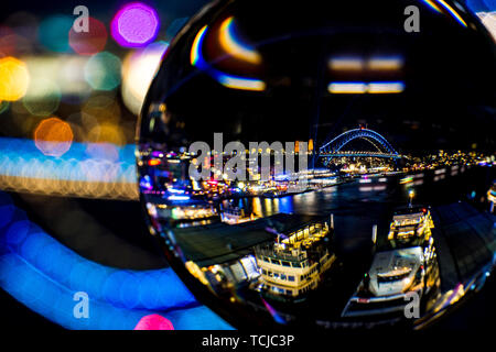 Una sfera di vetro rifrange il Porto di Sydney durante la vivida luce festival di Sydney, Australia. Foto Stock