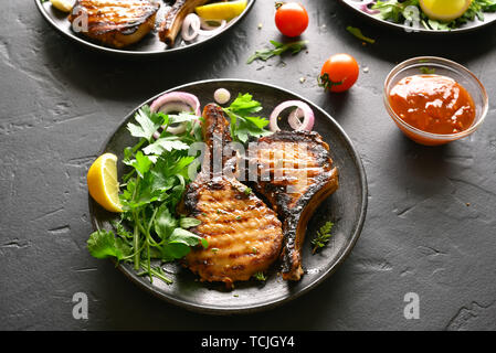 Gustose grigliate di carne di maiale bistecche sulla piastra sulla pietra nera tabella Foto Stock