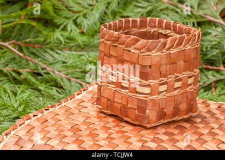 Tessuti a mano mat e cestello realizzato dal duttile di corteccia interna di un Western Red Cedar tree, poggiante su Western Red Cedar branchlets. Foto Stock