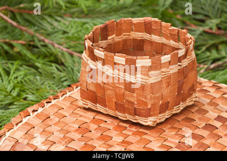 Tessuti a mano mat e cestello realizzato dal duttile di corteccia interna di un Western Red Cedar tree, poggiante su Western Red Cedar branchlets. Foto Stock