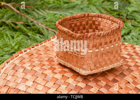 Tessuti a mano mat e cestello realizzato dal duttile di corteccia interna di un Western Red Cedar tree, poggiante su Western Red Cedar branchlets. Foto Stock