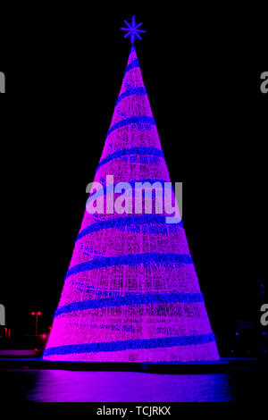 Il neon colorato albero di natale figura con luci contro uno sfondo nero Foto Stock