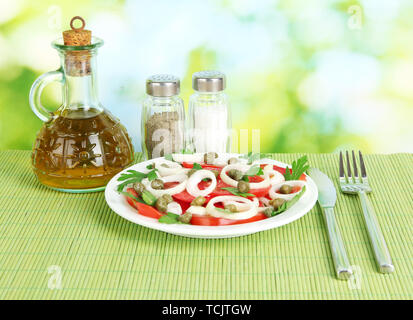 Insalata con capperi nella piastra sulla luminosa sullo sfondo verde Foto Stock