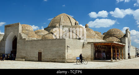 Margilan, Bukhara, Uzbekistan - 25 Aprile 2019: gli uomini di vendita pane uzbeko, non o lepeshka, il trasporto su una bicicletta, in background Toqi Zargaro Foto Stock