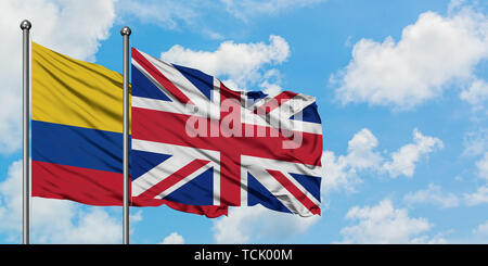 La Colombia e il Regno Unito bandiera sventolare nel vento contro bianco torbido cielo blu insieme. Concetto di Diplomazia e relazioni internazionali. Foto Stock