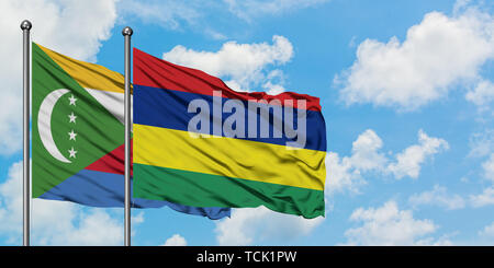 Comore e Maurizio bandiera sventolare nel vento contro bianco torbido cielo blu insieme. Concetto di Diplomazia e relazioni internazionali. Foto Stock