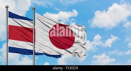 Costa Rica e Giappone bandiera sventolare nel vento contro bianco torbido cielo blu insieme. Concetto di Diplomazia e relazioni internazionali. Foto Stock