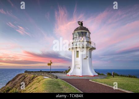 Faro con segnaletica a Cape Reinga al tramonto con nuvole rosa, estremo Nord distretto, Northland e North Island, Nuova Zelanda Foto Stock