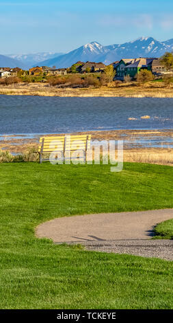 Sentiero panoramico e panca su un campo che si affaccia sul lago sotto il cielo blu in una giornata di sole Foto Stock