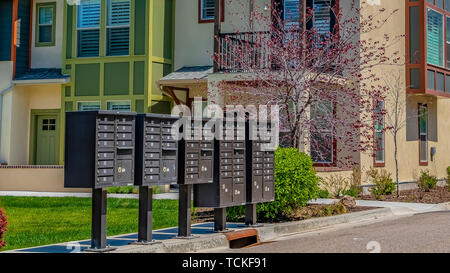 Telaio di panorama di cassette postali cluster sul marciapiede davanti alle case visto in una giornata di sole Foto Stock
