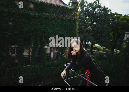 Bella bruna in posa su una scala di colore nero Foto Stock