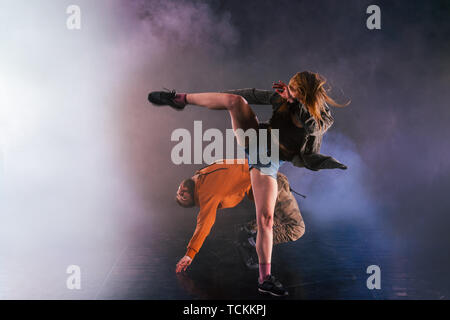 Coppia di danza si mette in mostra le loro mosse la ragazza sta gettando la gamba in alto nel cielo mentre l'uomo si inclina indietro verso il terreno. Foto Stock